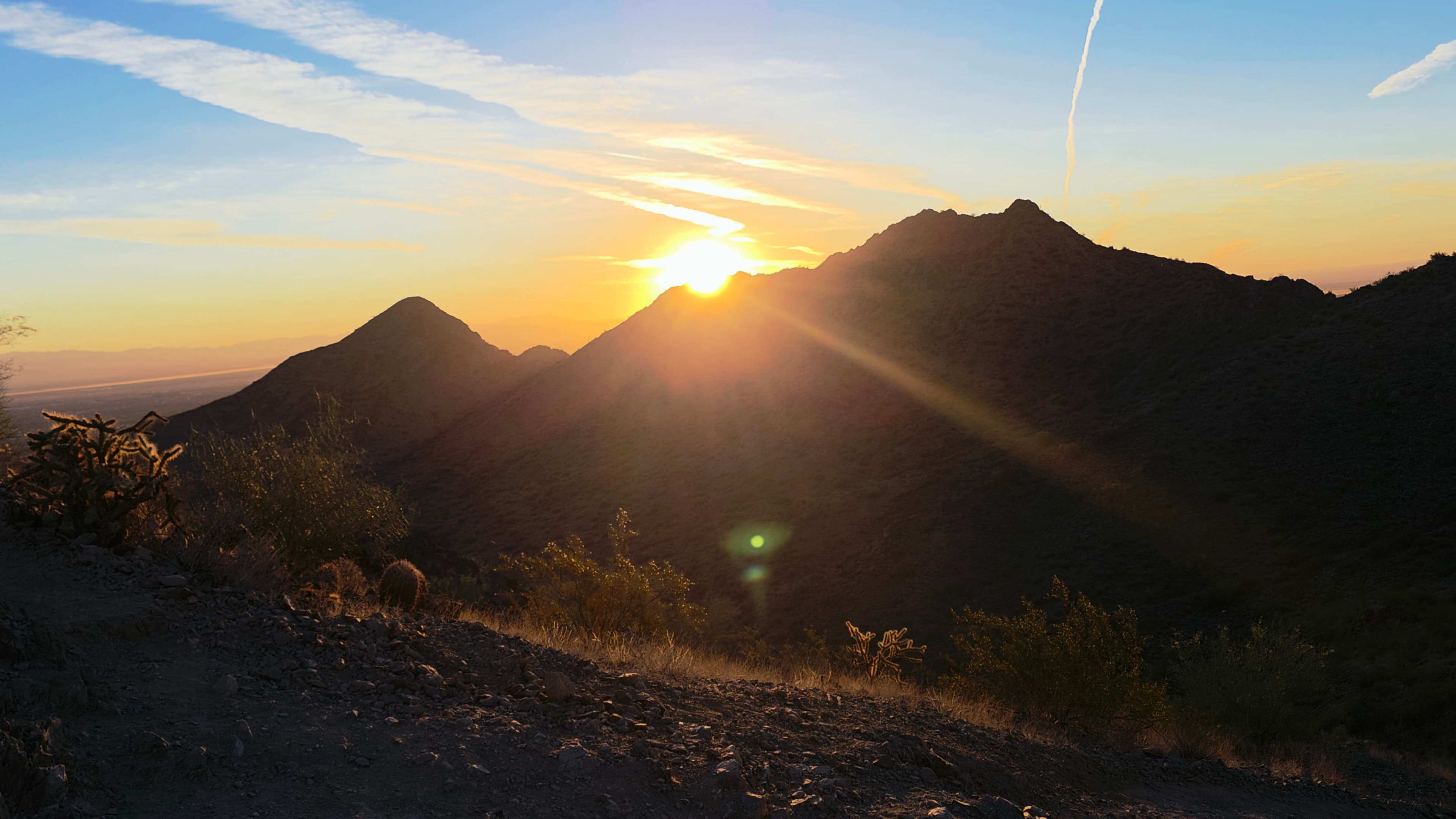 A serene desert sunrise piercing through layered mountain ridges with golden warmth breaking the morning silence.
