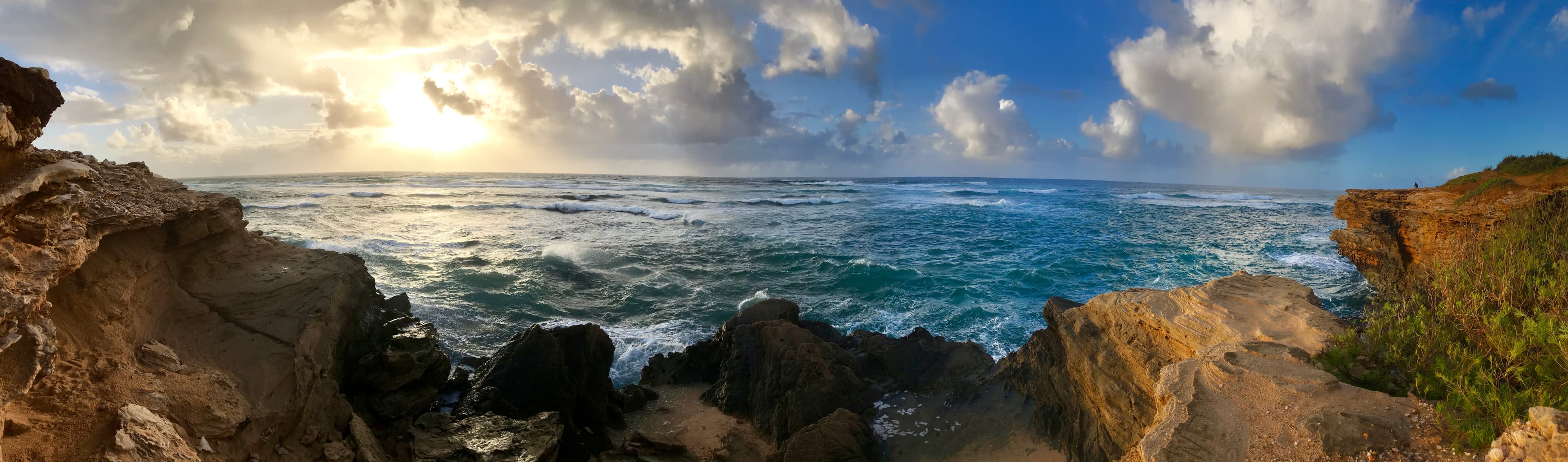 A moody coastal dawn where dramatic clouds and churning seas create an atmosphere of wild, untamed beauty against weathered limestone cliffs.